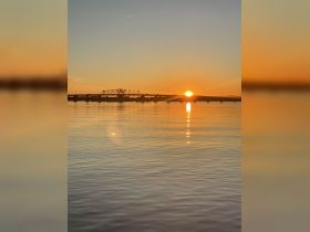 A stunning sunset over calm waters, with reflections creating a picturesque scene — perfect for capturing the beauty of nature during a boating trip.