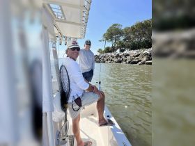 Two friends enjoy a sunny day fishing on a boat, showcasing the perfect outdoor adventure for fishing enthusiasts.