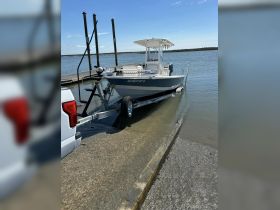 A fishing boat is being launched from a trailer at a dock, showcasing the vessel's sleek design and readiness for a day on the water.