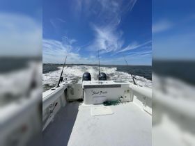The interior view of a fishing boat named 'The Slick Finish,' showcasing the helm and console as it speeds through the water, perfect for fishing enthusiasts.