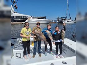 A group of kids proudly display their impressive catch of fish aboard a fishing boat, showcasing a fun day on the water filled with adventure and excitement.