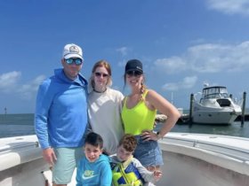 A cheerful family poses on the deck of a boat under a sunny sky, capturing a memorable moment during their boating adventure.