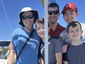 A cheerful family poses together on a boat, capturing a joyful moment under the clear blue sky — perfect for family adventures on the water.