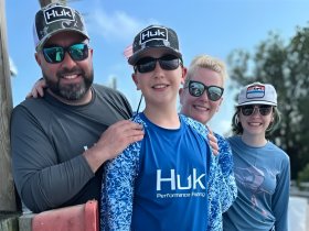 A cheerful family poses together, showcasing their excitement for a day of fishing and outdoor adventure. Perfect for capturing memorable moments on the water.