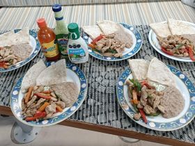 A delicious spread of grilled chicken and vegetables served with tortillas and sauces, perfect for a relaxing meal on board.