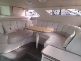 Interior view of a cozy lounge area on a boat, featuring comfortable seating and a table, perfect for relaxation while cruising.