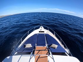A stunning view from the front of a yacht, showcasing the sleek design and tranquil ocean waters — perfect for a day of relaxation on the sea.