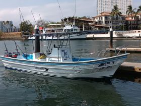 The Gilligan IV fishing boat is docked in a serene marina, showcasing its sleek design and fishing gear, perfect for a day on the water.