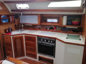 Interior view of a well-equipped boat kitchen, featuring wooden cabinetry and essential appliances, perfect for preparing meals while at sea.
