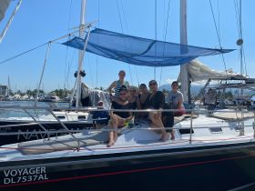 A joyful group of family and friends poses on the deck of a sailboat, ready for an exciting day on the water. Perfect for family outings and celebrations.