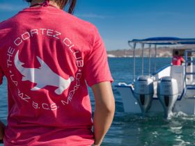 A member of the Cortez Club in La Paz, Mexico, stands by a boat, showcasing the vibrant atmosphere of marine adventures in the region.