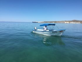 A speedboat named 'Oliver' glides through calm waters, showcasing a serene boating experience under clear blue skies.