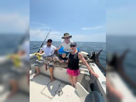 A group of friends celebrates their impressive catch while fishing on a boat, showcasing the thrill of a successful day on the water.