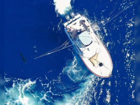 An aerial view of a fishing boat in action on the vibrant blue ocean, showcasing the thrill of deep-sea fishing adventures.