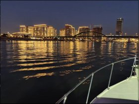 A serene night view from a boat showcasing a beautifully lit city skyline reflecting on the water — perfect for evening cruises and urban exploration.