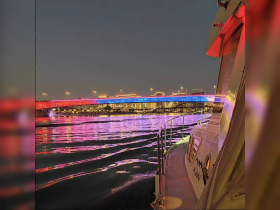 A stunning night view from the deck of a boat, showcasing a beautifully illuminated bridge and city skyline reflecting on the water — perfect for evening cruises.