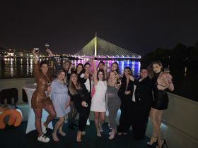 A lively group of friends celebrates on a boat at night, raising their glasses against a stunning illuminated backdrop — perfect for unforgettable parties and celebrations on the water.