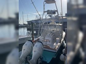 A detailed view of a fishing boat docked at the marina, showcasing its powerful twin engines and spacious deck, perfect for fishing adventures.