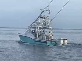 A fishing boat navigates the waters with crew members on board, showcasing the excitement of a fishing adventure.