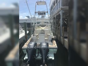 A clear view of a fishing boat docked at the marina, showcasing its twin engines and spacious rear deck, perfect for fishing adventures.