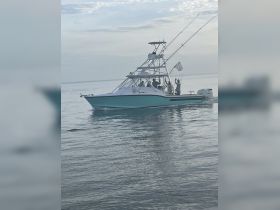 A fishing boat navigates through calm waters, with a group of people onboard enjoying their time on the water — perfect for fishing adventures and group outings.
