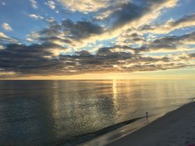 A stunning sunset over calm waters, reflecting vibrant colors on the beach — a perfect backdrop for serene coastal experiences.