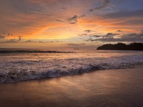A stunning sunset over the ocean, casting vibrant colors across the sky and reflecting on the beach — a perfect backdrop for memorable coastal experiences.