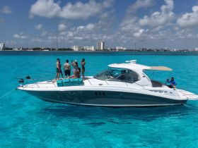 A lively group enjoys a day on the water aboard a sleek boat, surrounded by stunning turquoise waters — perfect for summer adventures and celebrations.