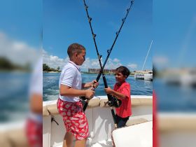 Two children enjoy a fun fishing experience aboard a boat, showcasing the excitement of fishing adventures on the water.