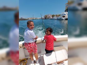 Two children enjoy a fun fishing experience on a boat, capturing the joy of family time on the water.