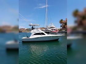 A sleek fishing yacht docked in a marina, showcasing its elegant design against a vibrant blue sky — perfect for fishing adventures or leisurely cruises.