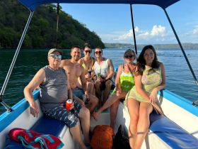 A cheerful group enjoys a sunny day on a boat, sipping drinks and soaking up the atmosphere — perfect for a fun day out on the water.