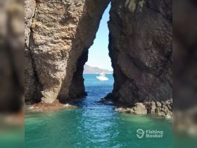 A stunning view through a natural rock arch, framing a boat in the turquoise waters — a picturesque scene perfect for exploring coastal landscapes.