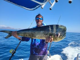 An angler proudly displays a large dolphin fish caught while fishing in the open ocean — a thrilling moment for fishing enthusiasts.
