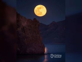 A stunning night scene featuring a full moon illuminating the landscape, with a boat gently gliding on the water — a perfect moment for night-time adventures.