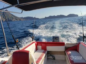 Interior view of a boat's seating area, showcasing comfortable red and white upholstery, perfect for relaxing while cruising through scenic waters.