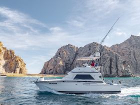 A sleek yacht named 'Go Deeper' cruises through clear waters, framed by stunning rocky cliffs — perfect for fishing or leisure outings.