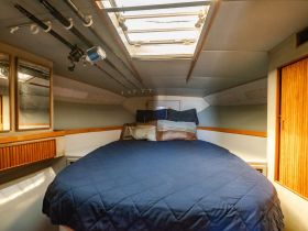 Cozy cabin interior featuring a comfortable bed and fishing rods, perfect for relaxing during a boating trip.
