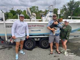 A cheerful group poses with their dog in front of a fishing boat, ready for an adventure with Fishing Beagle Adventures. Perfect for family outings or fishing charters.