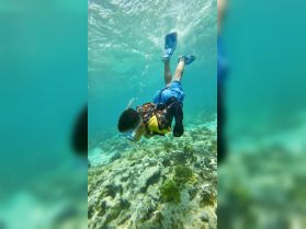 A child enjoys snorkeling underwater, exploring vibrant marine life and coral formations — a perfect adventure for young explorers.