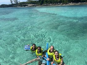 A joyful group enjoys snorkeling in the crystal-clear waters, showcasing a fun-filled day of aquatic adventure and exploration.