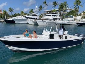 A joyful group enjoys a day on the water aboard a boat, showcasing smiles and a vibrant atmosphere against a backdrop of luxury yachts.