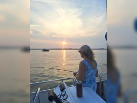 A woman enjoys a peaceful fishing experience at sunset on a boat, creating the perfect backdrop for relaxation and outdoor adventures.