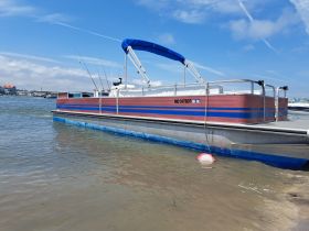 A vibrant pontoon boat docked in calm waters, showcasing its fishing gear and inviting atmosphere for a day on the water.