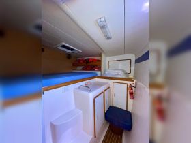 Interior view of a cozy cabin on a boat, featuring a comfortable seating area and storage space, ideal for relaxing during trips on the water.