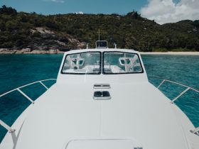 A stunning view from the front of a boat, showcasing its sleek design against a backdrop of lush greenery and clear turquoise waters, perfect for exploring coastal destinations.