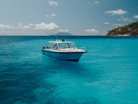 A sleek boat navigates through crystal-clear turquoise waters, showcasing the beauty of the marine landscape.
