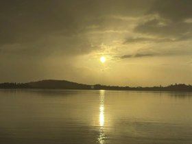 A serene sunset over calm waters, with reflections creating a picturesque scene — perfect for capturing the beauty of nature.