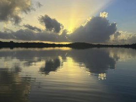 A stunning sunset over calm waters, reflecting the vibrant colors and clouds, creating a picturesque scene perfect for nature lovers and photographers.