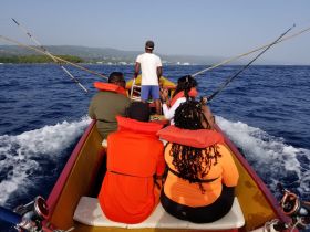 A group of friends enjoys a fishing trip on a vibrant boat, surrounded by the beautiful ocean — perfect for adventure seekers looking to reel in the catch of the day.